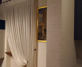 Il tessuto Agena a fili intrecciati per le tende raccolte con bracciali in rame brunito in un interno classico e moderno. Mariano Tende Verona.